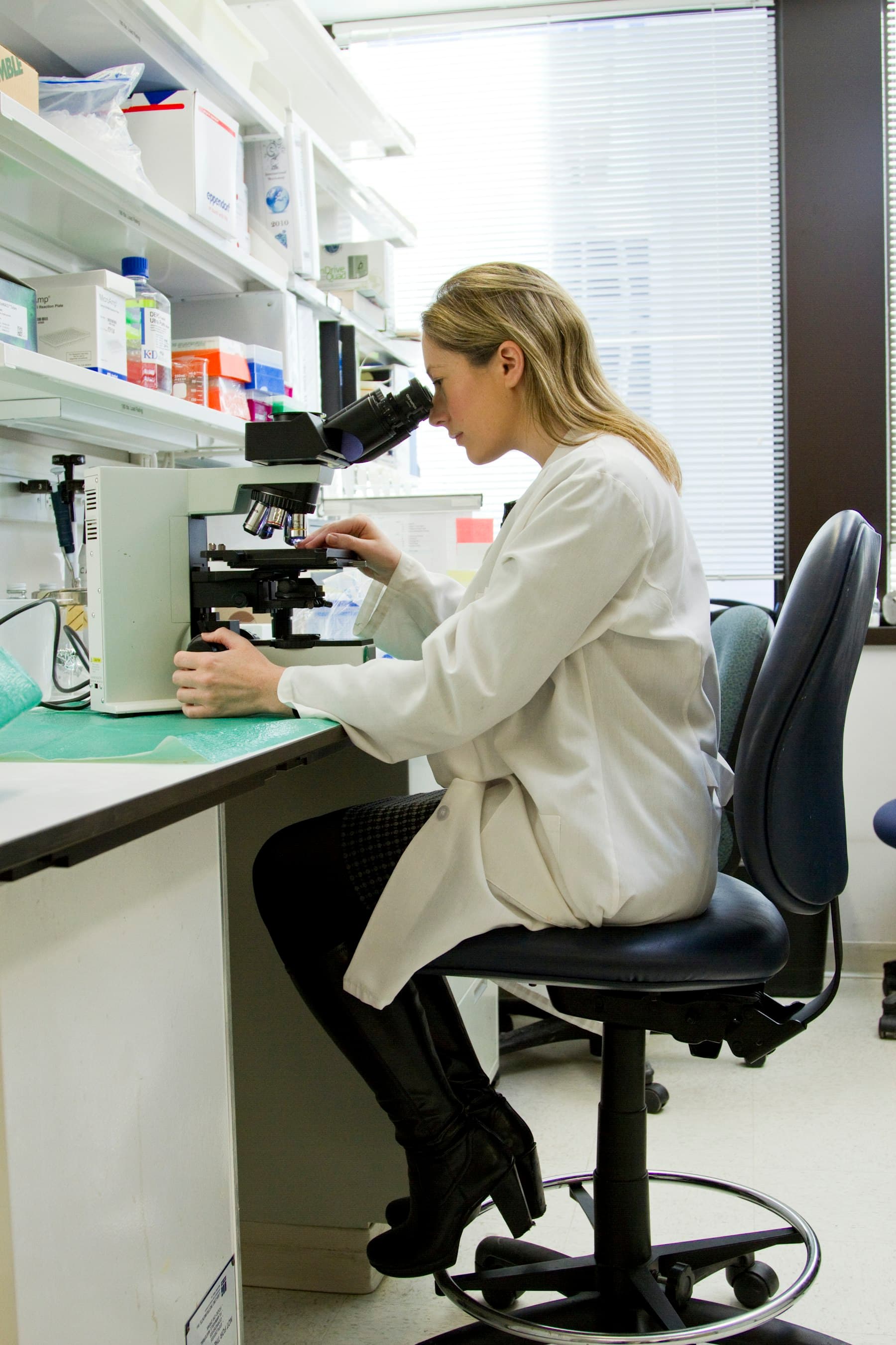 Lab technician reviewing samples under a microscope
